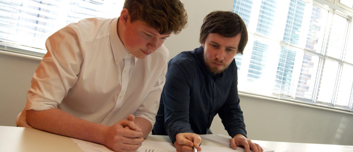  A man using a pen to point out locations on a map, another man watches.