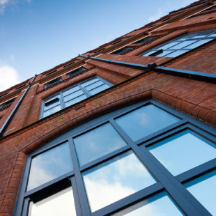  A skyward photograph looking up from the base of a building. With multiple windows in eye shot going up the building.